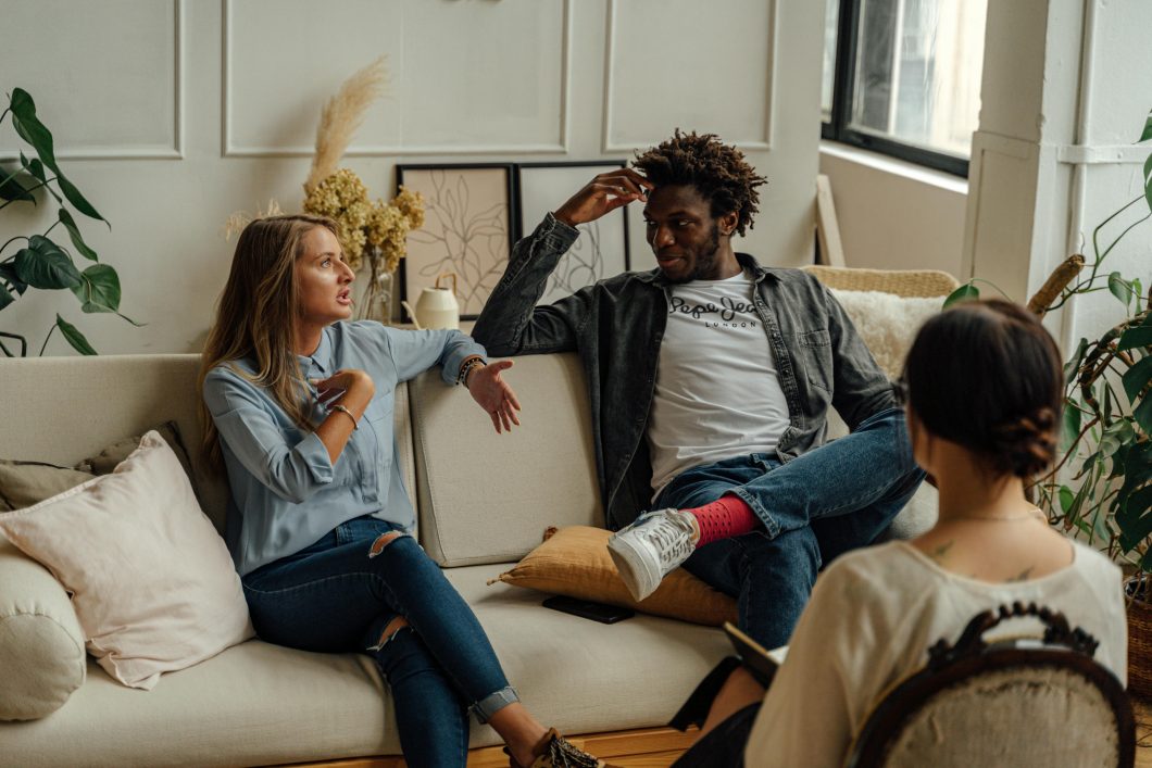 Couple sitting on a couch speaking to a therapist